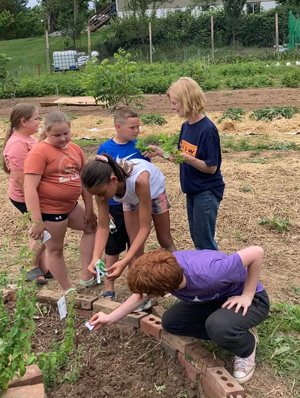 Dr Yoder at the Paoli Community Garden assisting kids with planting